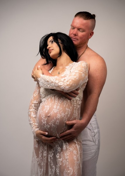 Intimate maternity couple portrait with lace gown and soft light