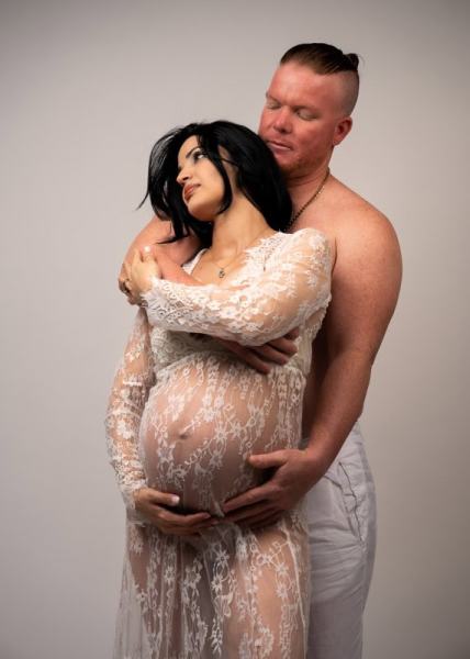Intimate maternity couple portrait with lace gown and soft light
