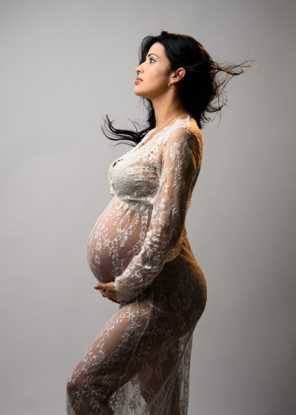 Empowering maternity photo in lace gown with dramatic lighting