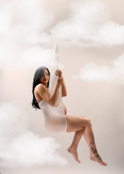 Dreamy maternity portrait floating among the clouds